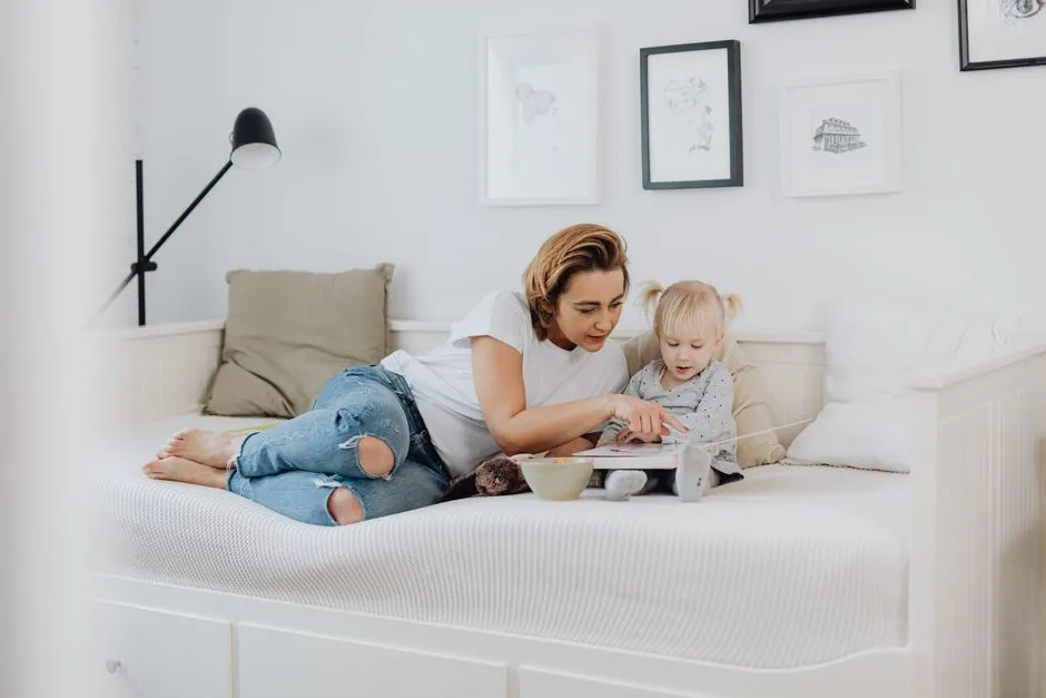 A parent lying beside a toddler, pointing at a picture book together